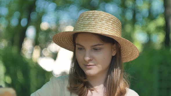 Smiling Lady Painter in Hat Looks at Cityscape and Draws