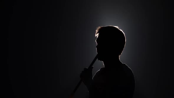 Silhouette of Bearded Man Blowes Smoke When Smoking Hookah on Black Background in Slow Motion. Close