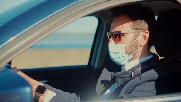 Self Isolation On Car On Covid19 Lockdown Coronavirus Quarantine. Man In Face Mask Driving Car.