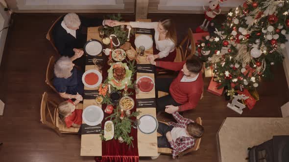 Whole Family Holds Hands and Prays Before Eating on Christmas Eve Top View