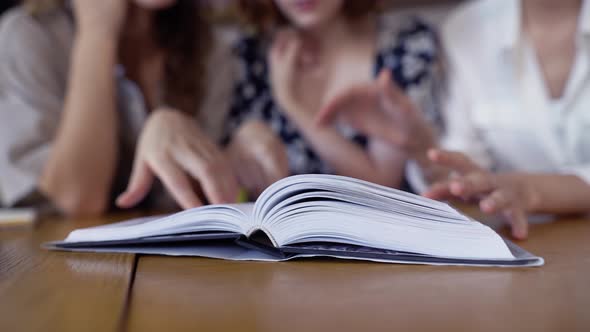 Unrecognizable Students Reading Book Together in the Library Closeup