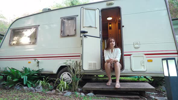 happy young woman sitting at door of a camper RV van motorhome