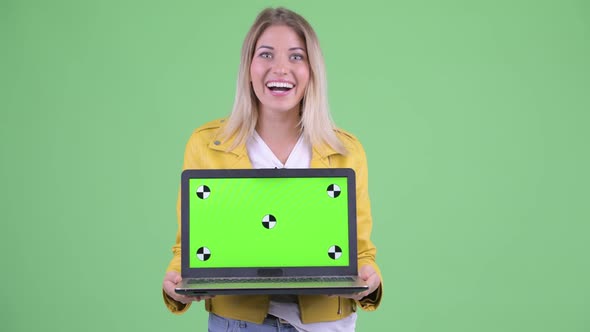 Happy Young Rebellious Blonde Woman Showing Laptop and Looking Surprised