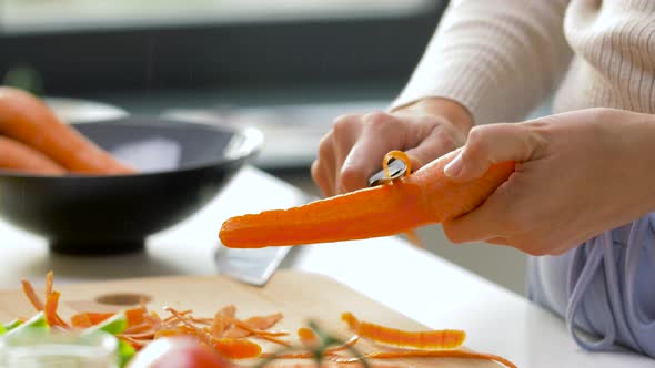 Hands Peeling Carrot with Vegetable Peeler