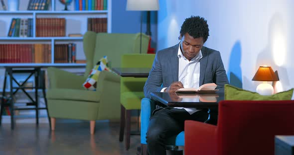Male African Student Reading a Book in the Library