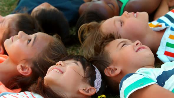 Close-up of schoolkids lying on grass