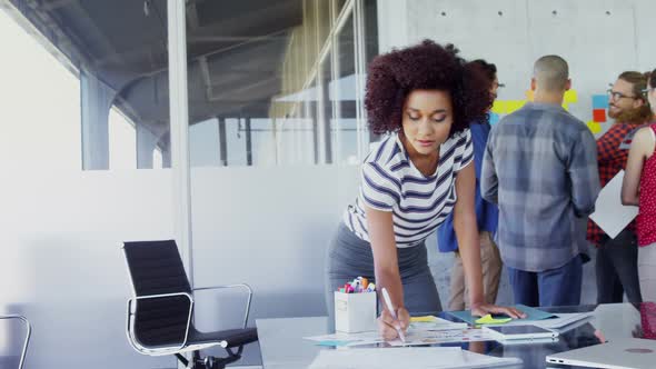 Woman working at table with her colleagues in background 4k