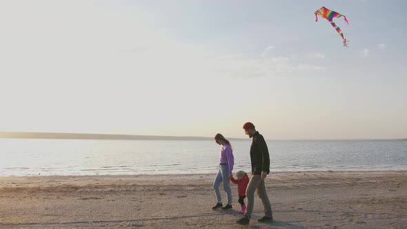 Happy Family Walking with Flying Kite at the Seashore During Sunset Slow Motion