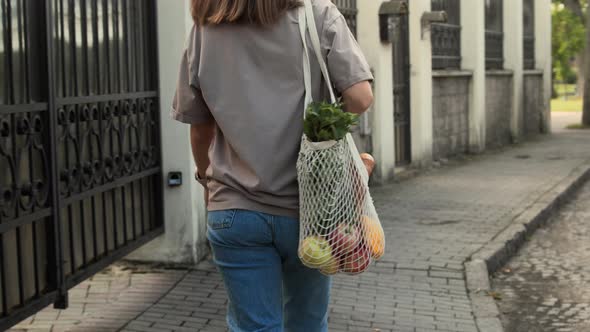 Woman walks outside with mesh string knitted shopping bag