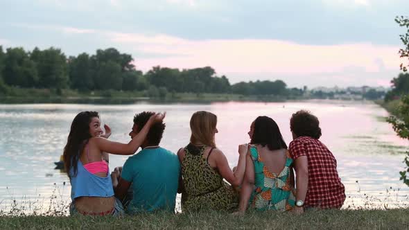 Back view of group of friends enjoying in nature, talking and laughing