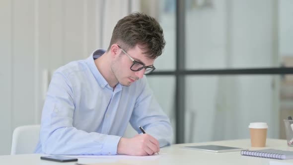 Pensive Young Man Writing on Paper Thinking