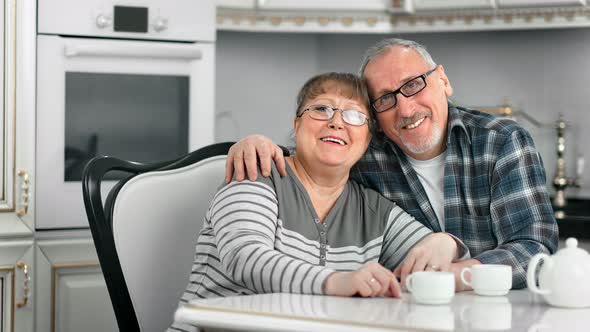 Friendly Elderly Family Embracing Enjoy Coffee Break Relaxing Together at White Cuisine Interior