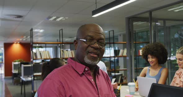 Portrait of african american businessman smiling over diverse business colleagues talking