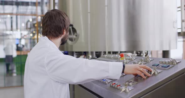 A Male Brewer with a Beard at Brewery Factory Working Behind the Control Panel Dashboard