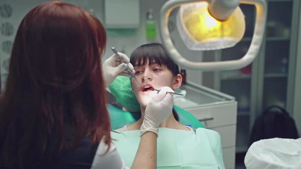 Dental clinic. Woman dentist working at her patients teeth