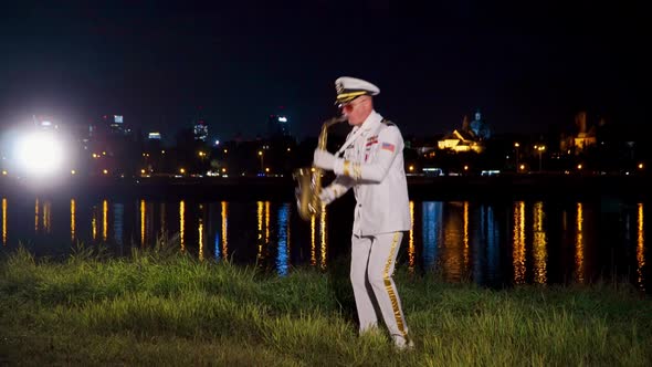 Saxophonist Plays at Night By the River