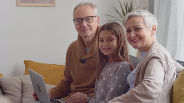 Grandparents and Granddaughter with PC on Sofa