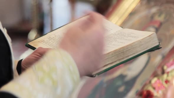 Priest holds a holy ancient bible in his hands and prays