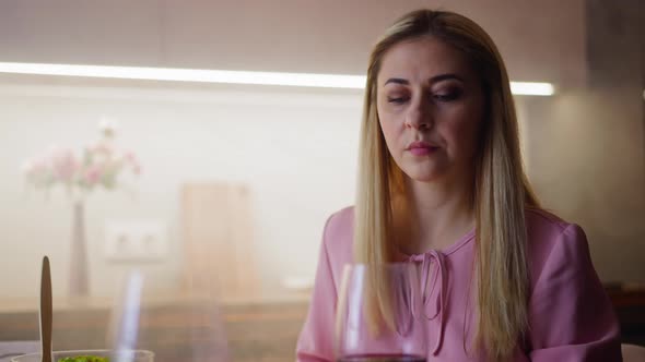 Upset Woman Looks at Glass with Wine Suspecting Poisoning