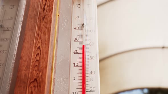 The outdoor thermometer at the garden attached to the wooden window. Warm-season