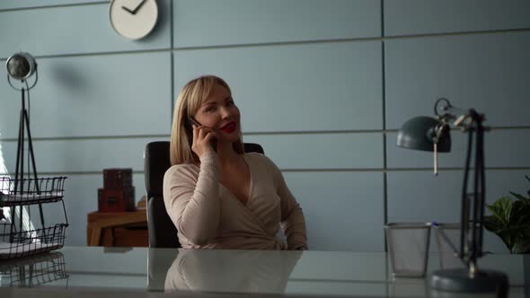 Woman Is Relaxing in Her Office Room at Break Time, Talking By Mobile Phone