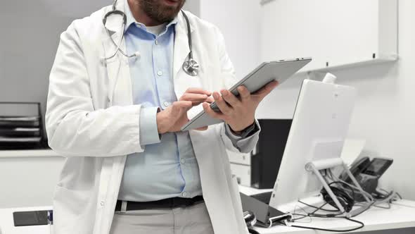 Male Doctor with White Coat and Stethoscope Using Tablet Network Connection in Hospital Room Medical