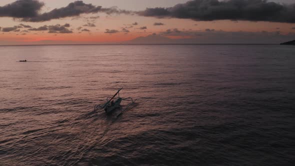 Aerial View of Sunrise Above Ocean with Dark Silhouettes of Fishing Boat Going for Fishery