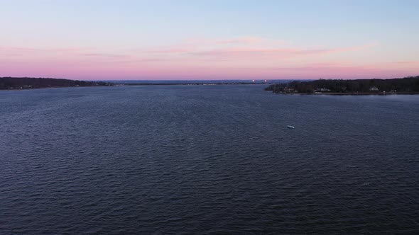 an aerial shot over a serene bay during a beautiful sunrise. The sky is pink and blue with a few clo