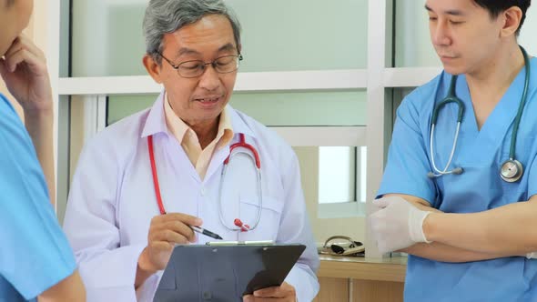 Team of asian doctor nurse consult together on patients file at hospital.