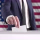 Voting. Man Putting a Ballot into a Voting Box with USA Flag on Background. - VideoHive Item for Sale