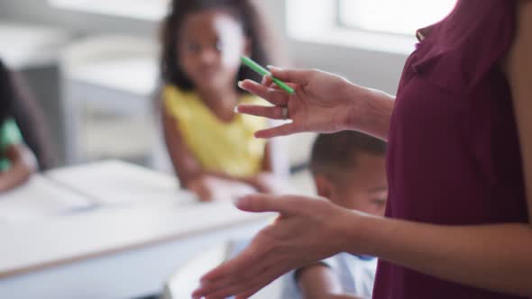 Video of midsection of caucasian female school teacher studying diverse children in classroom