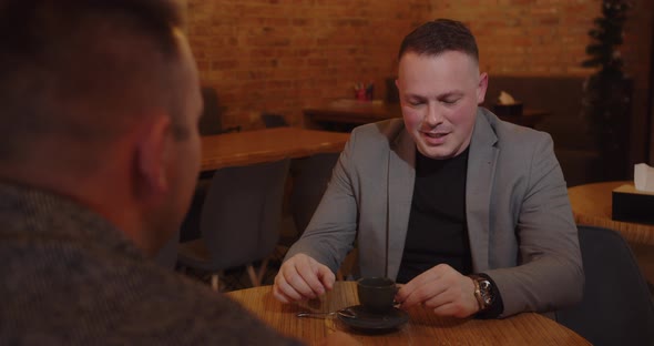 Two Men In A Cozy Cafe Are Having Business Talks And Drinking Coffee