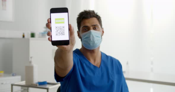 Portrait of Male Nurse in Safety Mask Showing Vaccinated Qr Code on Cellphone at Camera