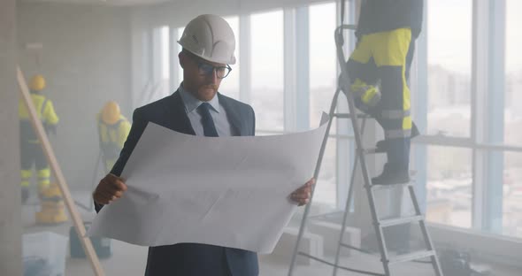 Young Male Architect at Construction Site Reviewing Blueprint