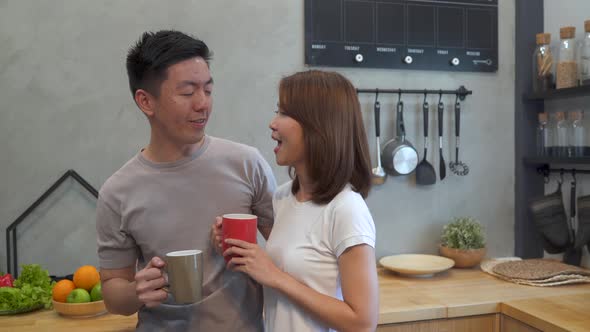 Asian couple are drinking a cup of coffee together talking while having breakfast.