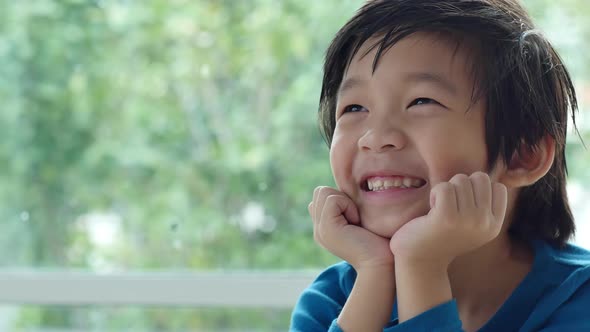 Cute Asian Child Resting Chins On Hands On Wood Table