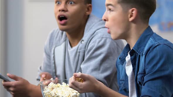 Excited Teenagers Eating Popcorn and Watching Tense Crime Drama on Cable Tv