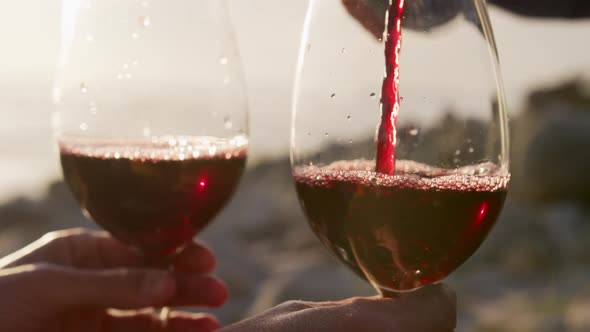 Man pouring wine by the sea