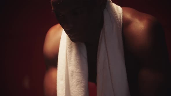 Black Handsome Young Man Sits in a Locker Room with a Towel Around His Neck Light Reflecting