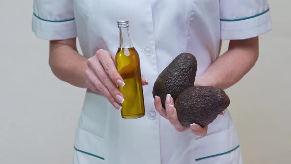 Nutritionist Doctor Holding Organic Avocado Fruit and Bottle of Oil