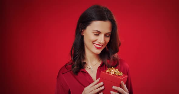 Beautiful Woman Enjoys a Valentine's Gift on a Red Background