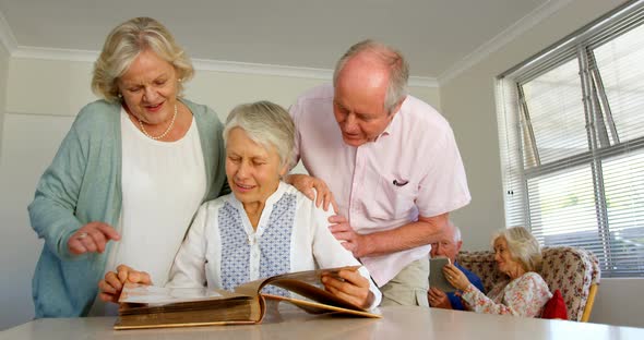 Front view of active Caucasian senior people looking at photo album in nursing home 4k