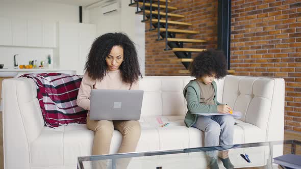 Portrait of a Curly Girl in Glasses Working with a Laptop