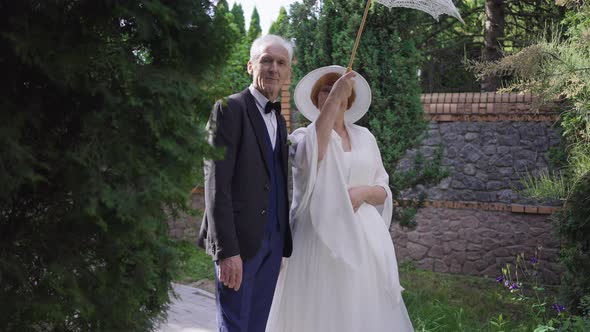 Romantic Loving Senior Couple in Wedding Dress and Suit Posing with Sun Umbrella in Slow Motion