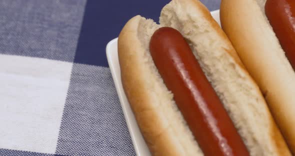 Close up pan across a plate of hot dogs with ketchup, mustard, and relish on the side.