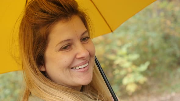 Caucasian blond woman outdoor with yellow umbrella 4K 2160p 30fps UltraHD footage - While raining bl