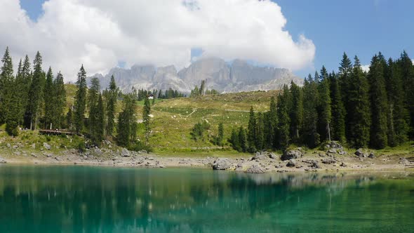 The video shows the view from the center of Lake Carezza. The mountains and the trees are reflected