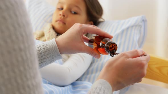 Mother Pouring Cough Syrup for Sick Daughter