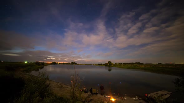 Time lapse at dusk overlooking lake with fishermen and traffic lights