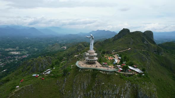 Aerial of a Jesus Christ Statue in Tana Toraja Sulawesi at the top of a mountain with tourists and s